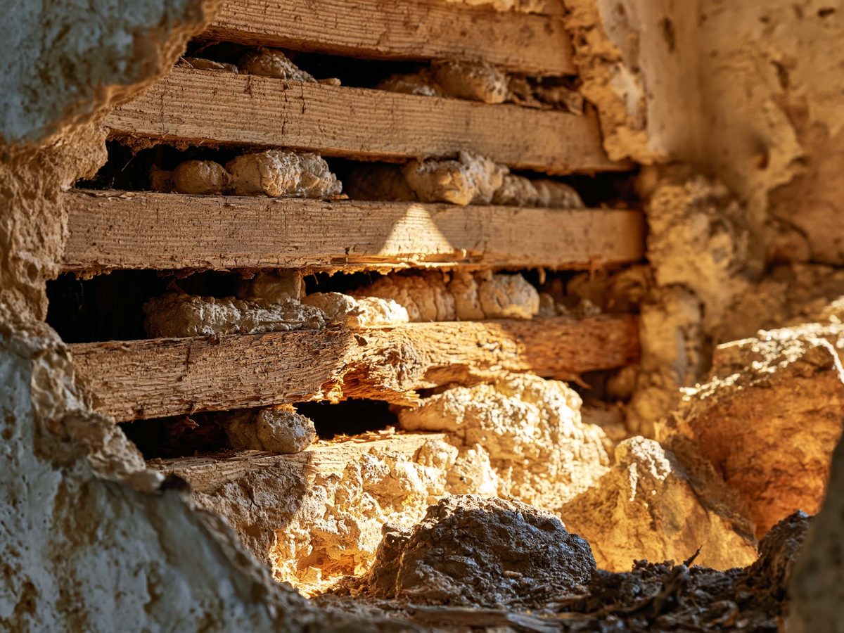 An opening in an old wall showing wood lath with the original plaster keys squeezed through and hardened behind it