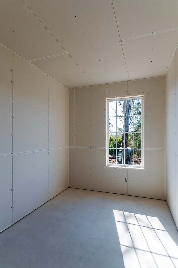 A room with new drywall hung and the seams taped, waiting to be finished